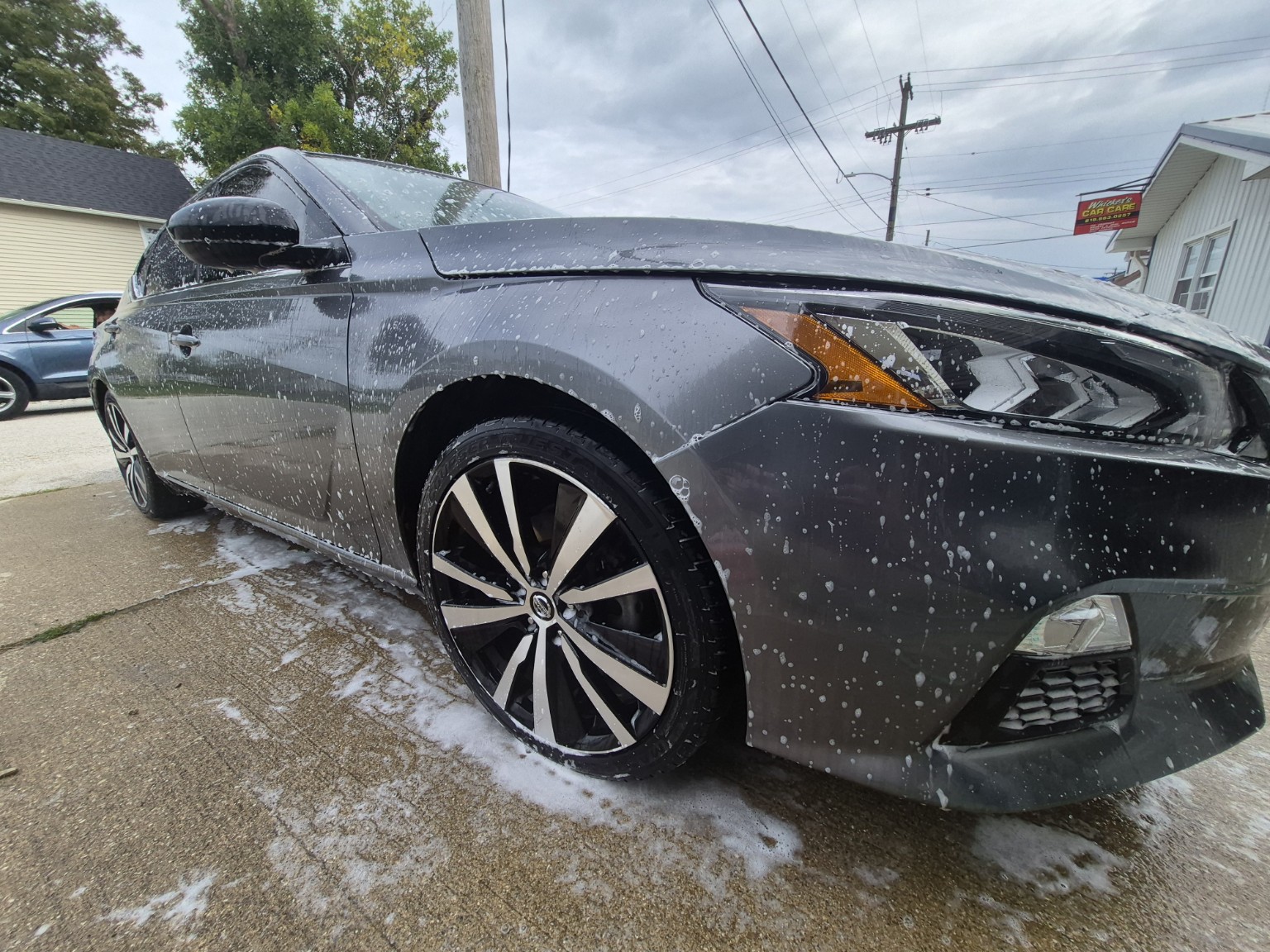 Gray Nissan receiving a foaming exterior wash