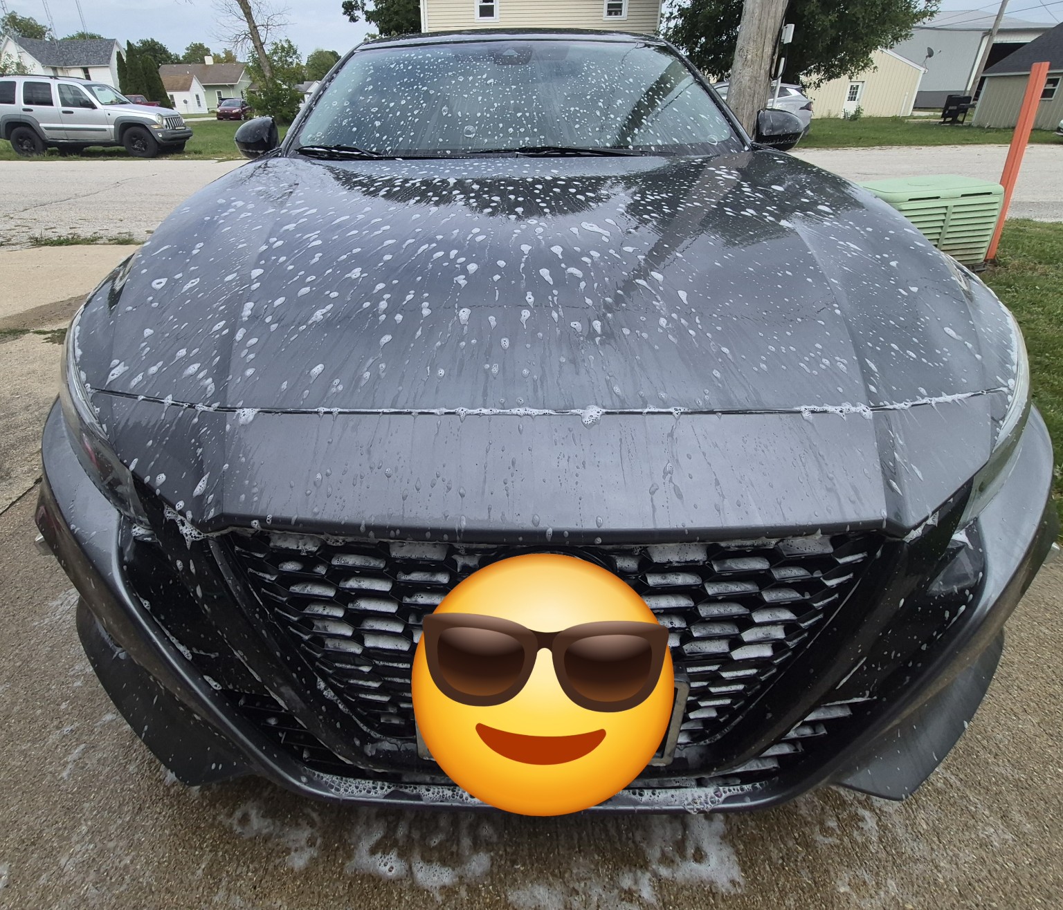 Front of gray Nissan covered in soap during exterior detailing