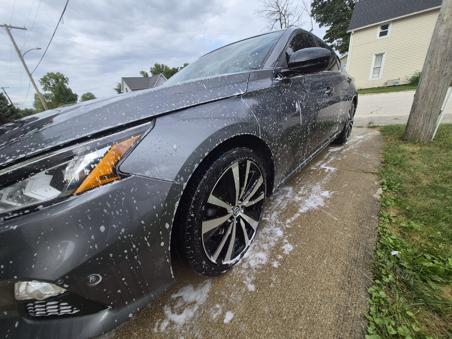 Side of gray Nissan covered in soap during exterior detailing